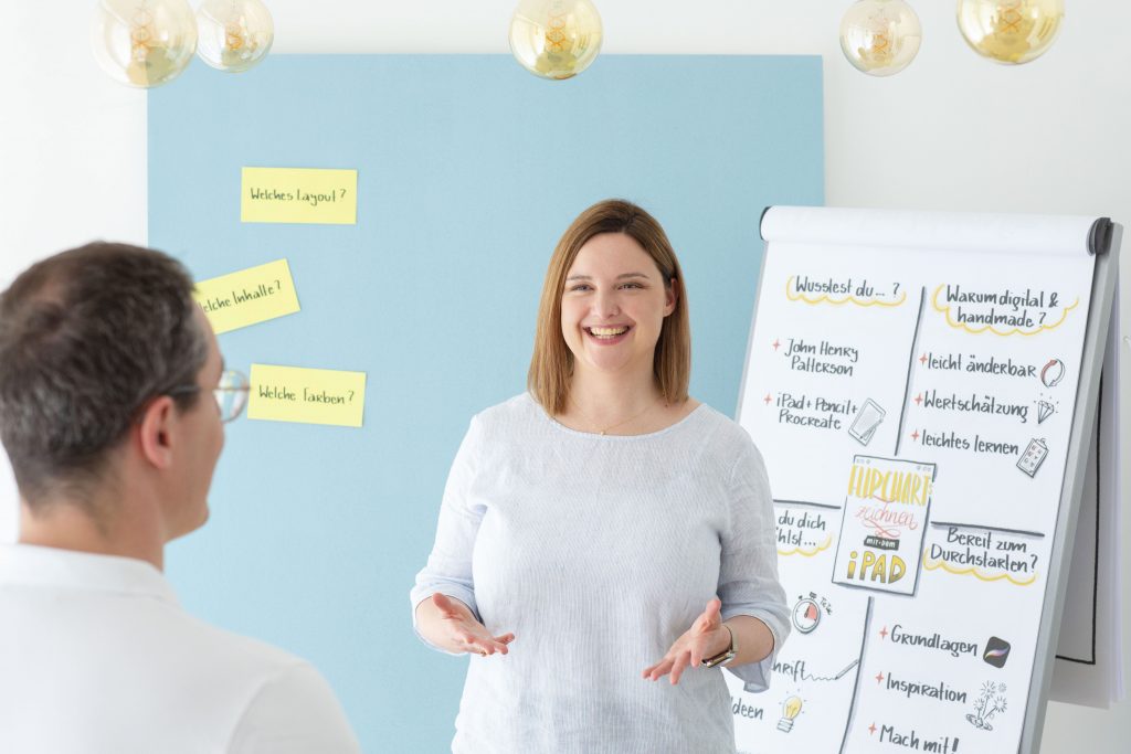 Trainingssituation mit Trainerin und Teilnehmer vor einem Flipchart im Handmade Design und Moderationskarten auf einer Pinnwand